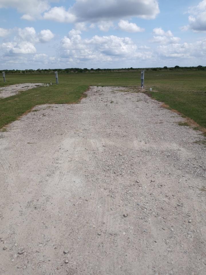 Spacious gravel RV sites with electric pedestals and open green fields — monthly contractor housing near Ineos Alvin TX
