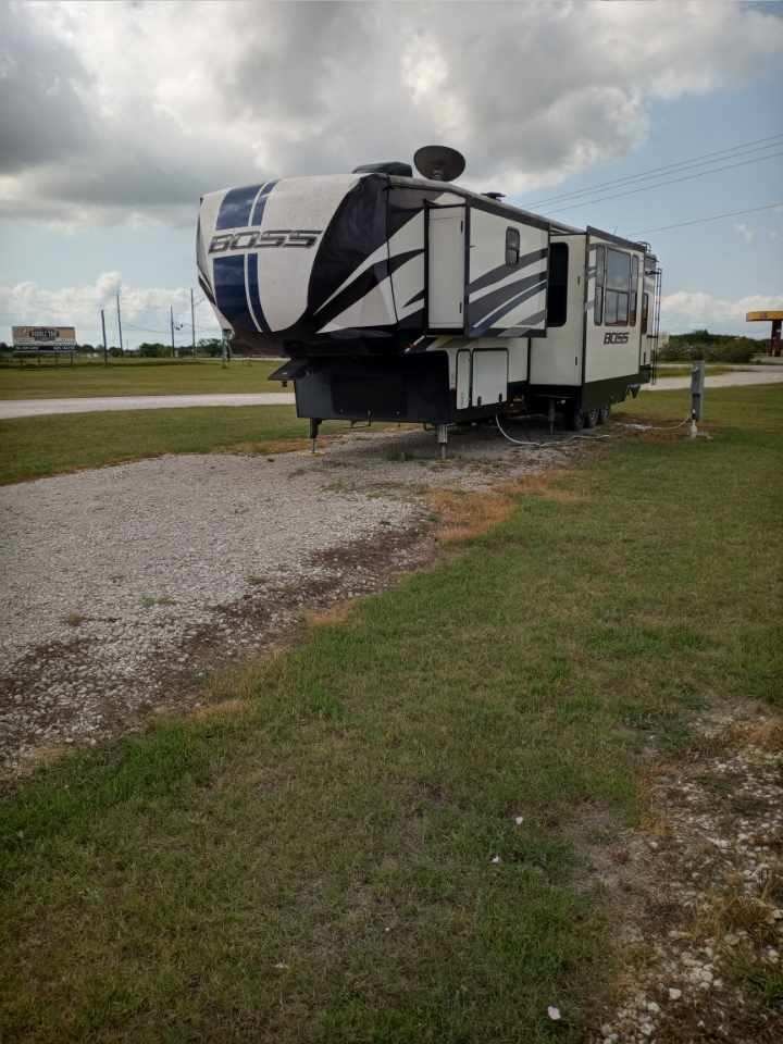 Boss fifth-wheel trailer set up at a full hook-up concrete-and-gravel RV site at Double Time RV Park in Alvin, Texas
