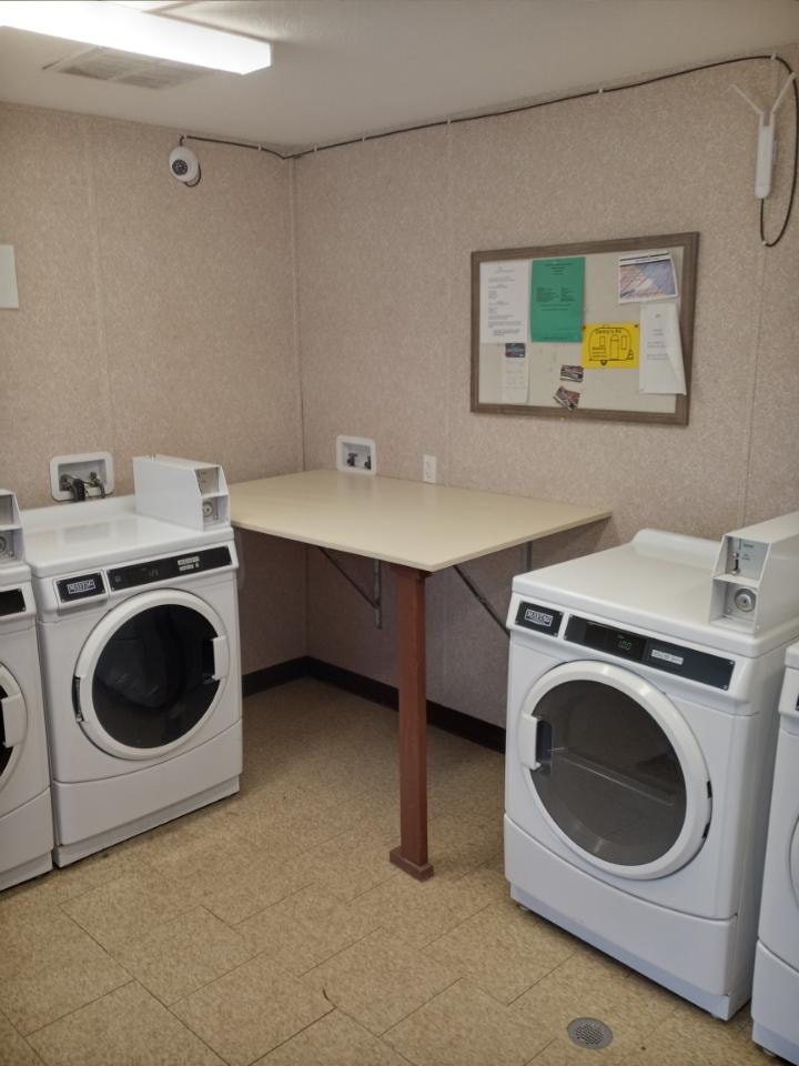 24-hour on-site laundry room with coin-operated washers, dryers, and folding table at Double Time RV Park Alvin TX — available for all guests