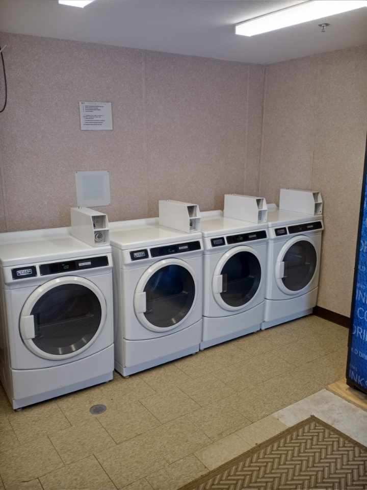Four commercial coin-operated dryers in the 24/7 laundry facility at Double Time RV Park — full-service amenities for long-term stays in Alvin TX